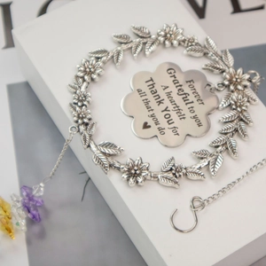 Detail of engraved flower pendant on silver leaf bracelet with colorful crystal beads