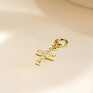 Macro shot of gold cross charm with clear cubic zirconia stones and metal ring