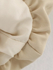 Detailed macro view of the cream and beige ruched fabric texture on this stylish jacket