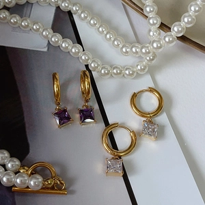 Detail of 18k gold plated stainless steel earrings with purple and white square zircon