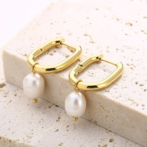 Detailed macro view of U-shaped gold earrings with elegant hanging white pearls