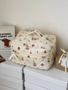 Close-up of quilted beige makeup bag featuring cute circus bear print and ribbon detail