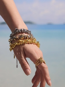 Macro shot of punk style gold and silver spiked bracelets and layered ring on model