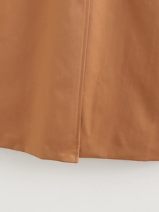 Detailed close-up of caramel cotton blend coat side slit and bottom hem stitching