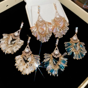 Close-up of elegant fan-shaped tassel earrings with pearls and crystals on black velvet