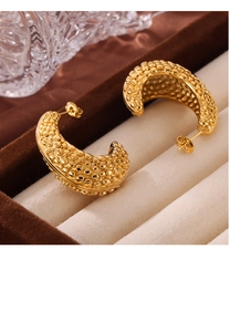 Macro detail of gold-plated pebbled texture C-shape earrings in a velvet box