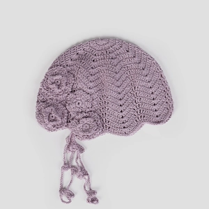 Detail view of handmade crochet beret with lavender floral accents and tassel ties
