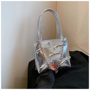 Close-up of silver textured handbag with metallic bows and a delicate bead chain strap