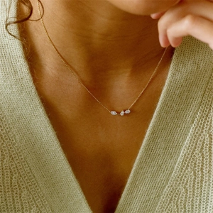 Detail of three pear-cut crystals on a gold chain necklace worn over a green cardigan