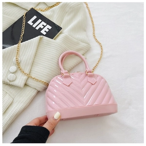 Detailed view of pink jelly bag featuring V-shaped texture and gold metal chain strap