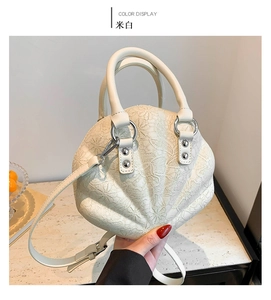Detail of cream white shell bag with elegant lace texture and detachable chain strap