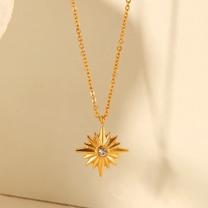 Close-up of golden sunburst pendant necklace with a central sparkling crystal stone