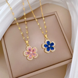 Close-up of titanium necklaces with five-petal flower pendants in pink and blue stones