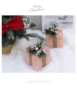 Close-up of a pink plush Christmas gift box ornament with pine needles and burlap ribbon