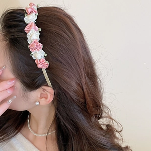 Detailed side view of 3D fabric flower headband in soft pink and white tones