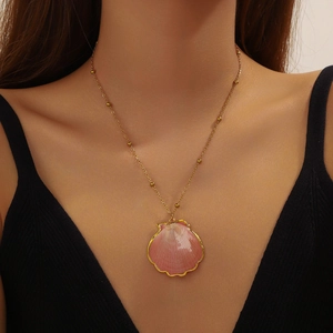 Close-up of a pink seashell pendant with gold edges on a gold beaded chain necklace