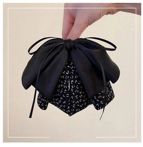 Macro detail of multilayer bow hair claw clip featuring black satin and leopard print fabric