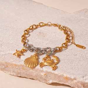 Detailed close-up of gold sea star, shell and crab charms on a bicolor metal chain