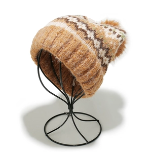 Close-up of Fair Isle knit beanie with camel geometric patterns and a brown faux fur pom