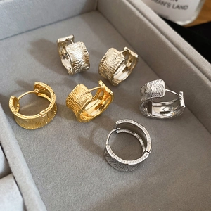 Detailed view of 18K gold and silver wide hoop earrings with irregular textured surface