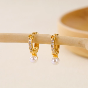Detail view of gold-plated hoop earrings featuring white pearls and clear cubic zirconia
