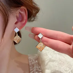 Elegant geometric gold and white square earrings featuring amber-like stone textures