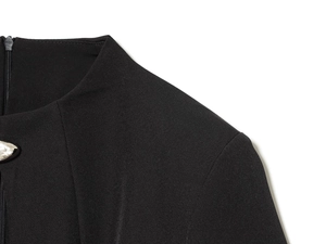 Détail du décolleté de robe noire avec fermeture éclair invisible et pendentif métal