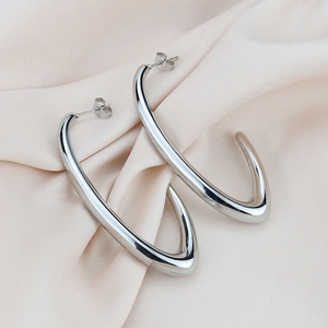Close-up of high-polish silver U-shaped hoop earrings on elegant beige silk fabric
