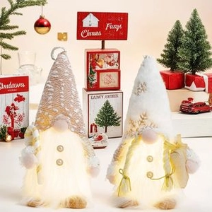 Close-up of plush glowing Christmas gnomes with warm LED lights and knitted hats