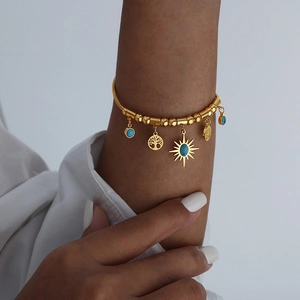 Golden beaded bracelet with tree of life and blue turquoise charms on a model wrist