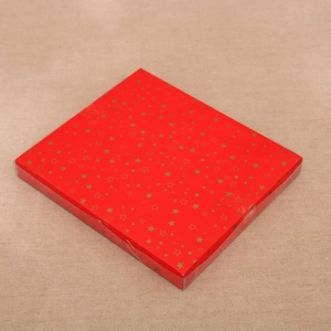 Detailed view of a red Christmas gift box with gold star patterns on a textured cloth