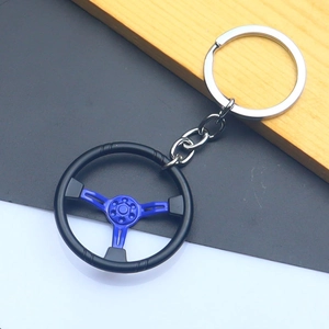 Close-up of a racing steering wheel keychain in black and blue zinc alloy on a wooden desk