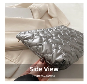 Detail of silver metallic puffy clutch bag with heart quilting held against beige blazer