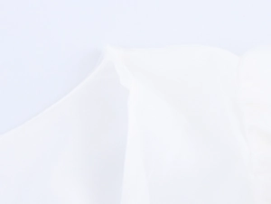 Détail du tissu en maille blanche avec texture fleurie 3D et coutures de manches bouffantes
