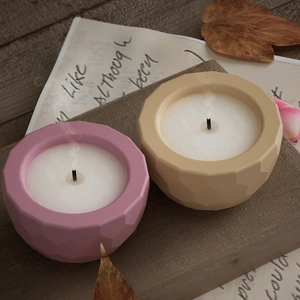 Macro detail of geometric faceted candle jars in pastel pink and beige matte ceramic