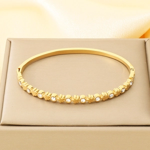 Detail of gold-plated bangle featuring white zircon inlay and clover patterns