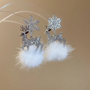 Detailed close-up of sparkling reindeer and snowflake earrings with soft white pom poms