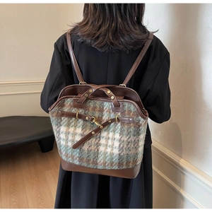 Detail of retro plaid backpack with brown leather straps and metal hardware on model