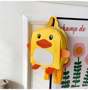 Detailed view of yellow cartoon duck backpack for toddlers hanging on a wall