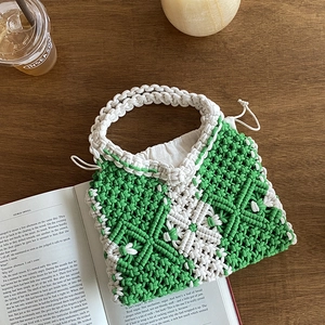 Handmade woven cotton rope tote bag with green hollow patterns on a wooden table