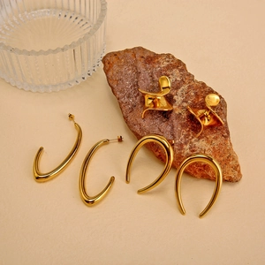 Close-up of geometric 18K gold-plated irregular stainless steel earrings on a rustic stone