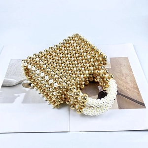Detail of handmade beaded handbag with gold metal beads and white pearls on a magazine