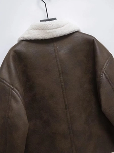 Detail of dark brown faux suede jacket featuring a contrast white faux fur collar and back stitching