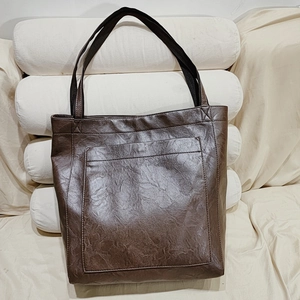 Vue détaillée du sac cabas marron foncé avec texture cuir froissé et poche frontale