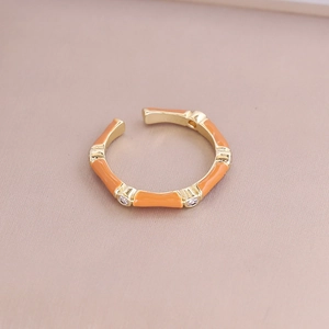 Detail of bamboo-style adjustable ring with orange enamel and zircon accents