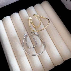 Close-up of gold and silver irregular twisted metal ear cuffs in a jewelry box
