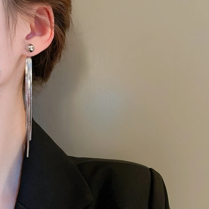 Detail of silver long tassel earrings worn by a model showing elegant metallic drape