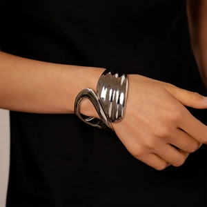 Polished silver geometric open cuff bracelet shown on model with asymmetric cutout design