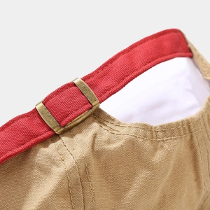 Detail of adjustable brass buckle and red strap on khaki washed cotton hip hop cap