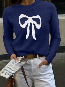 Close-up of dark blue knit sweater with white bow pattern and soft texture detail